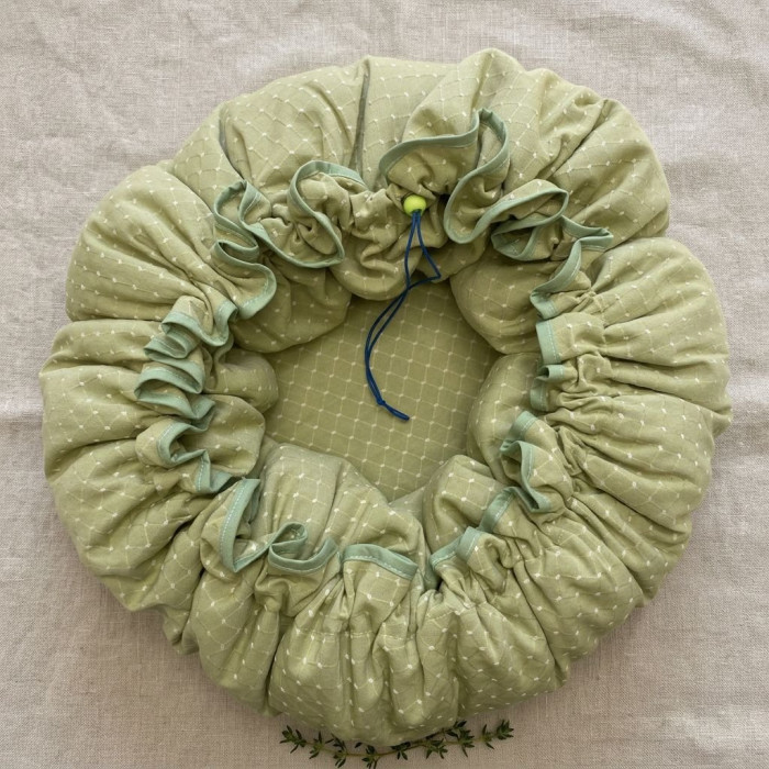 Snood élastique vert clair à pois blancs, profondeur et drapé froncé, fond lin beige. Parfait pour rester au chaud. Marmite norv
