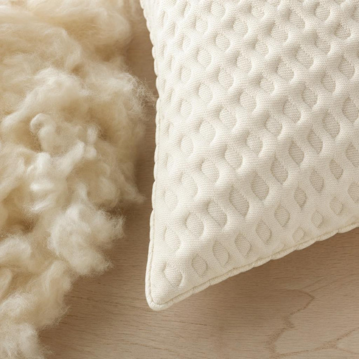 Gros plan du tissu matelassé et de la laine naturelle de l'oreiller garni laine
