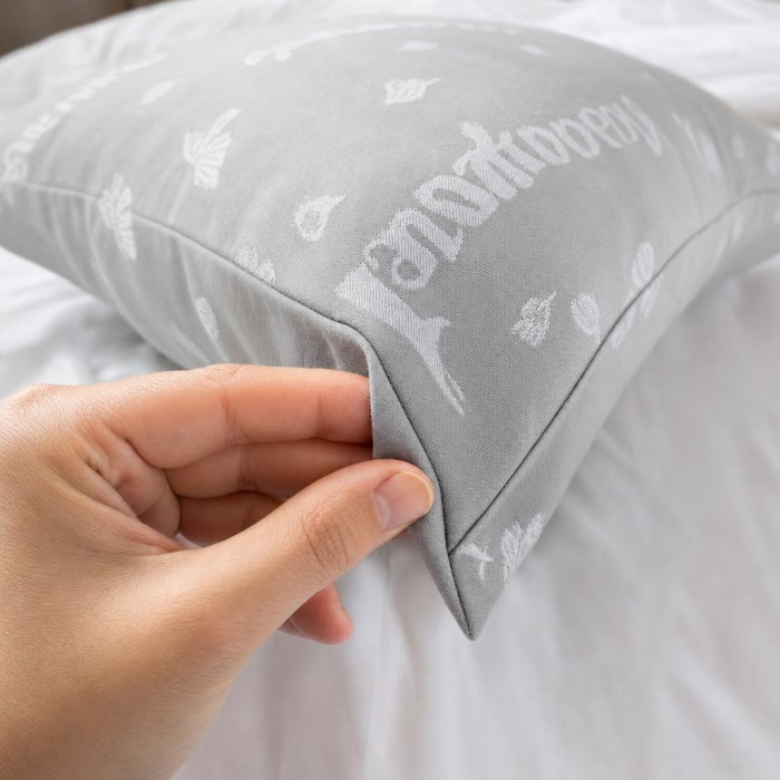 Main pinçant l'épaisse toile à matelas de l'oreiller Grand-Mère