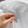 Main pinçant l'épaisse toile à matelas de l'oreiller Grand-Mère